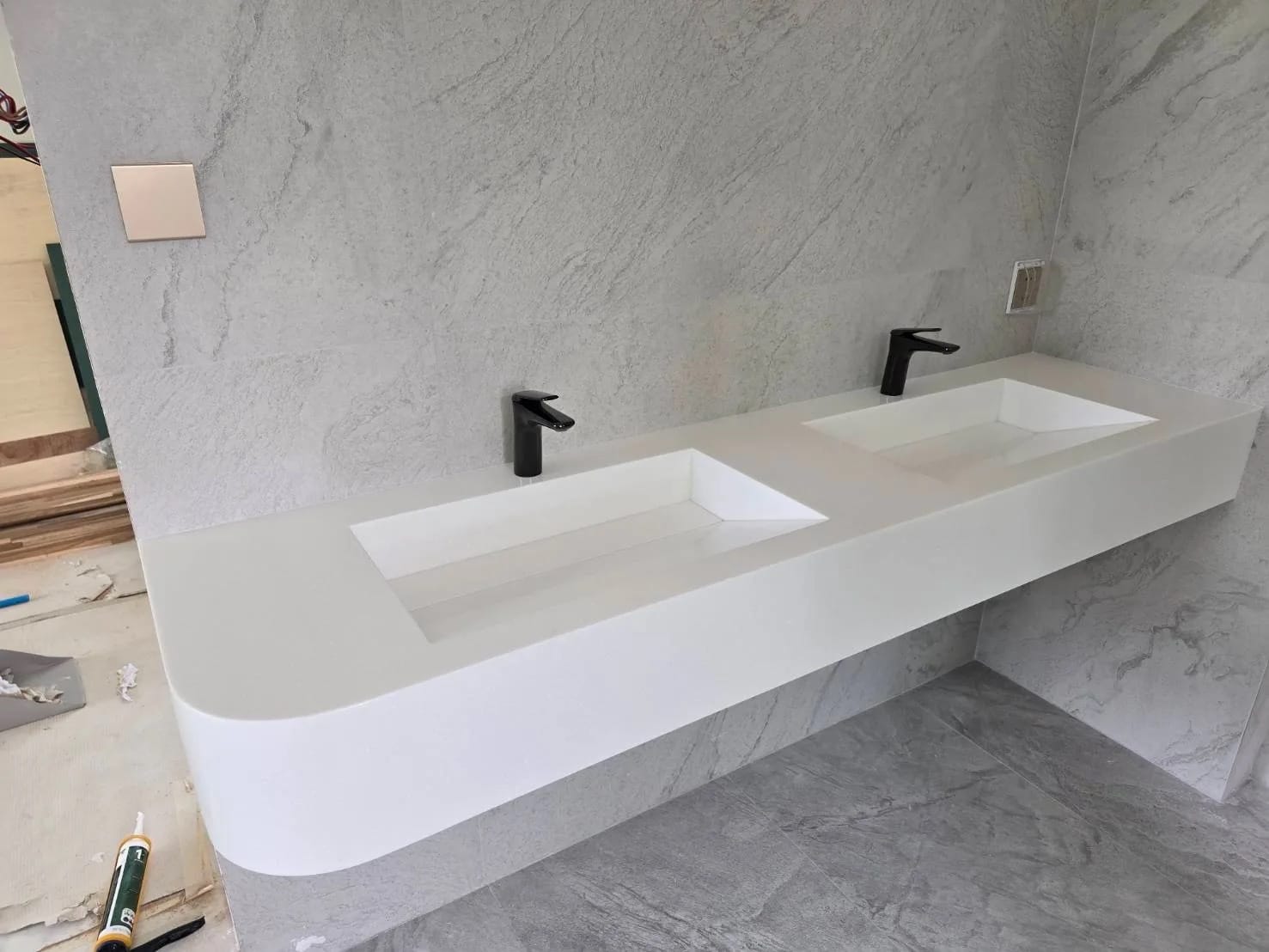 Wall-hung solid-surface vanity with two integrated basins and a rounded end