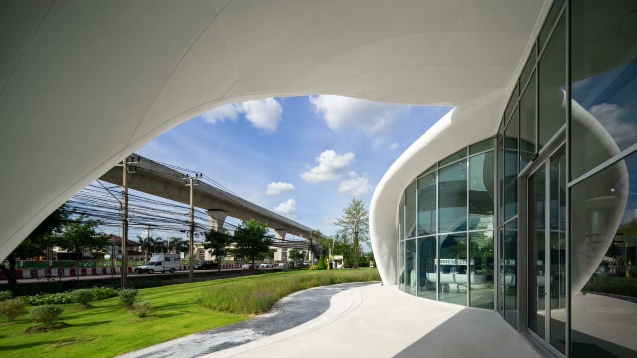The curved white solid-surface canopy of a showroom, seen from its glass front